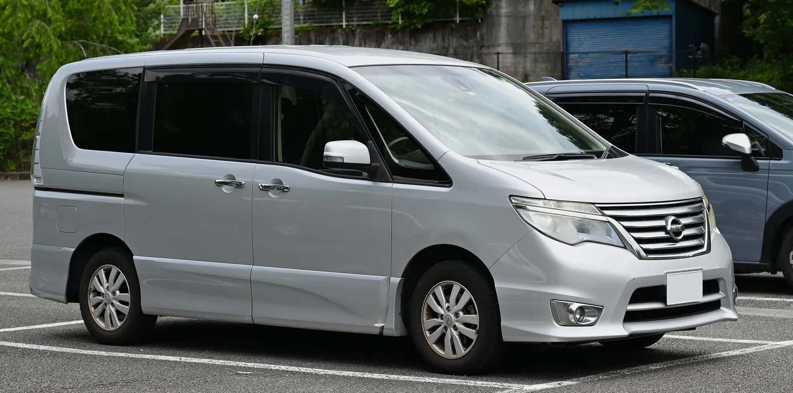 Silver Nissan Serena Highway Star people carrier parked in a car park with green trees behind