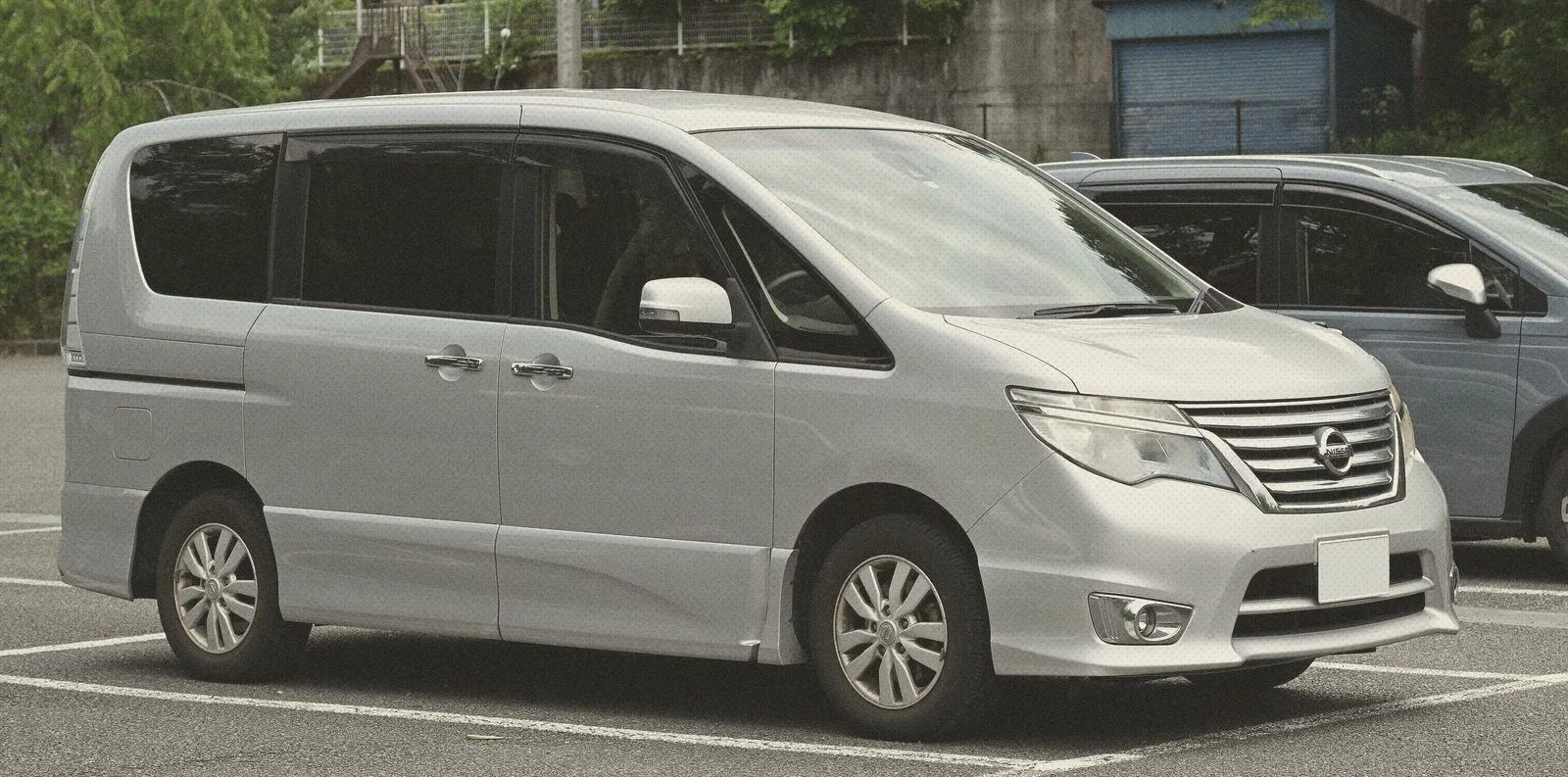 Silver Nissan Serena Highway Star people carrier parked in a car park with green trees behind