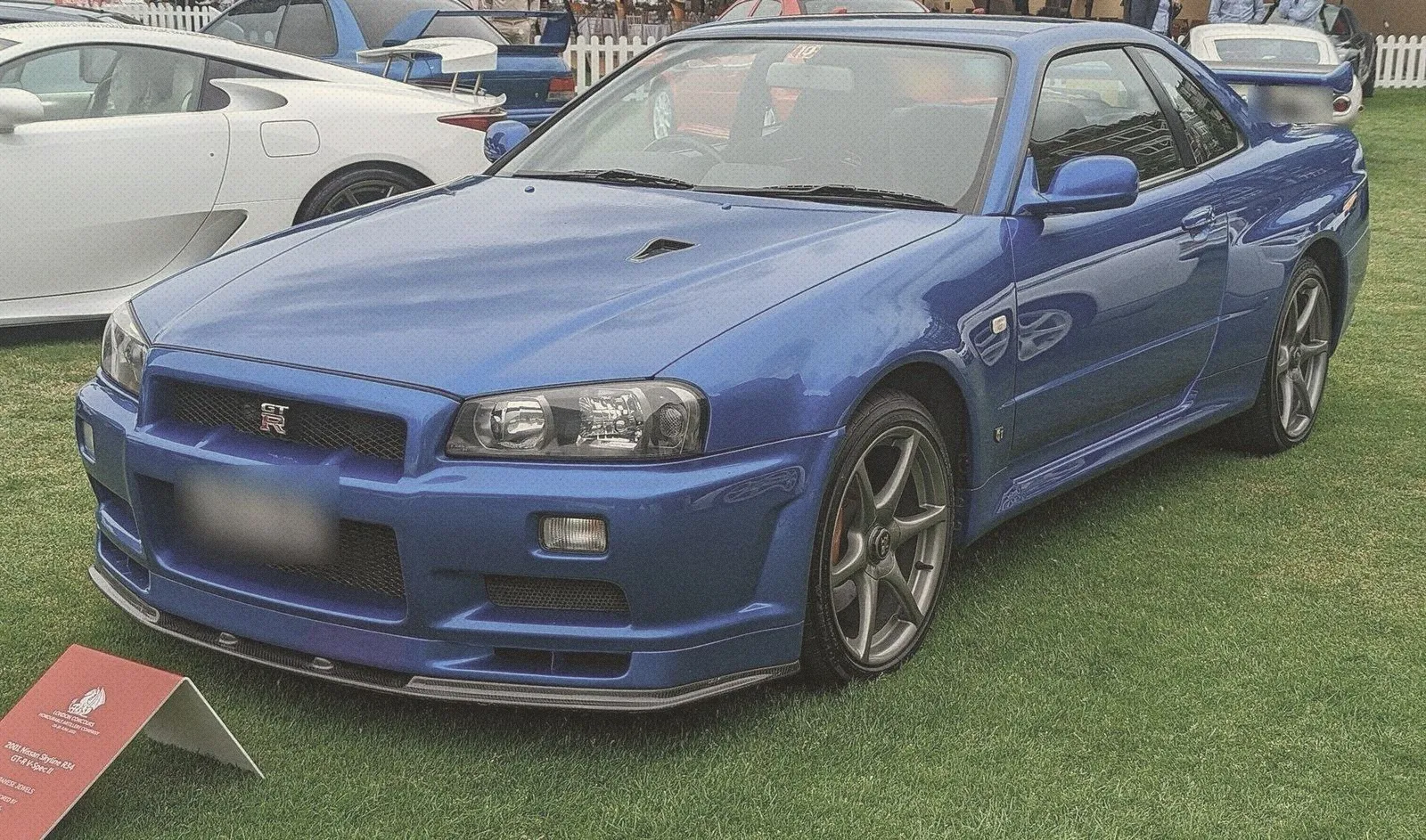 Bayside Blue Nissan Skyline GT-R R34 displayed on a grass lawn at a car show